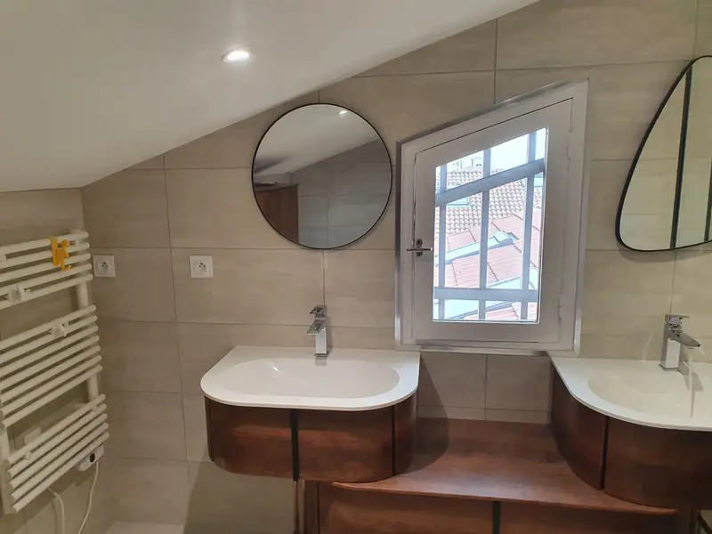 Salle de bain avec double vasque, miroirs ronds et radiateur sèche-serviettes
