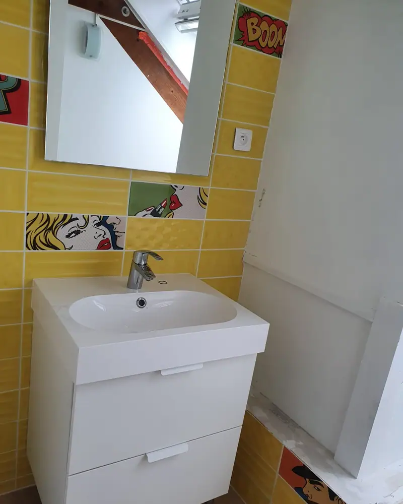 Salle de bain à carrelage jaune avec meuble vasque blanc et WC suspendu