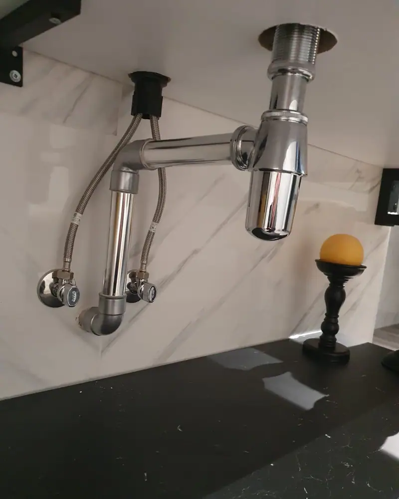 Siphon chromé installé sous un lavabo