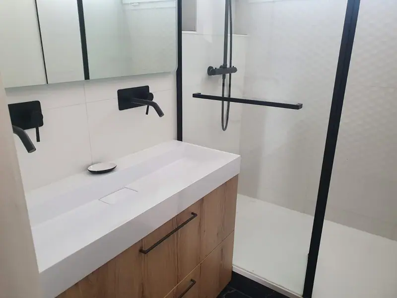Vasque à poser sur meuble bois, robinetterie noire et douche vitrée